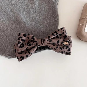 Détail d'une pince à cheveux à motif léopard avec étiquette dorée sur fond blanc