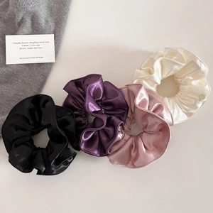 Quatre chouchous élégants en satin aux couleurs noir, violet, rose et crème vus de dessus