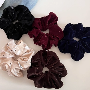 Dettaglio di cinque elastici per capelli in velluto a pois in colori assortiti con etichetta