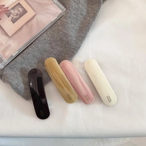 Detailed view of four acetate hair clips in black, amber, pink, and ivory finishes