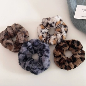 Set of four plush leopard print scrunchies in various shades on a white flat lay background