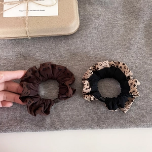 Detailed view of two leopard print scrunchies in dark brown and beige polyester fabric