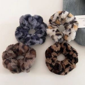 Detailed view of plush leopard print scrunchies in four animal pattern color schemes