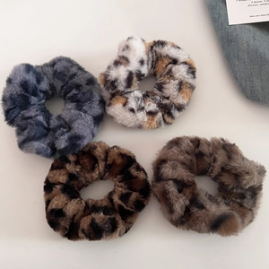 Detailed view of four leopard print plush scrunchies in varied autumn colors and textures