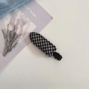 Close-up of black and white plaid fabric hair clip on aesthetic magazine background