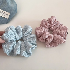 Close-up of pink and blue hollow lace crochet scrunchies with fine knit texture