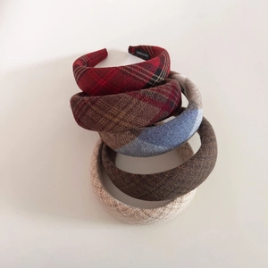 Detailed close-up showing a variety of five plaid wool headbands with handmade labels
