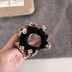 Close-up of leopard print and black fabric scrunchie with detailed stitching and soft texture