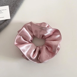 Vue détaillée du chouchou en satin nacré rose avec une texture plissée élégante