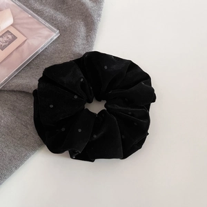 Primo piano di scrunchie in velluto nero a pois su maglia grigia con accessori eleganti