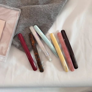 Detail showing seven acetate hair barrettes in marbled wine red and tortoiseshell patterns