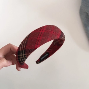 Detail of red plaid sponge headband showing handmade tag and tweed fabric texture