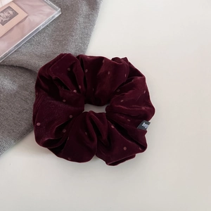 Dettaglio dell'elastico in velluto bordeaux con discreto motivo a pois per capelli