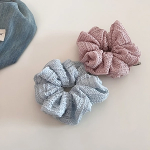 Close-up of light blue and pink lace scrunchies with intricate hollow-out floral patterns