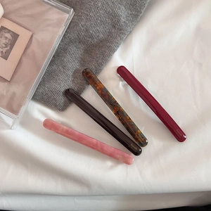 Detail of four acetate hair barrettes in marble, amber, and burgundy tones