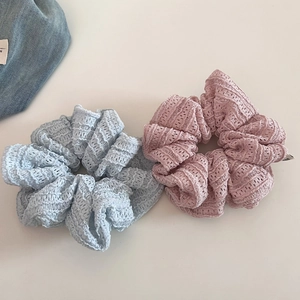 Close-up of light blue and pink lace scrunchies with intricate hollow-out floral textures
