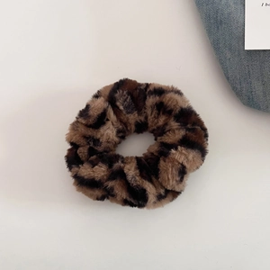 Macro shot of plush leopard print scrunchie showing soft faux fur texture and pattern