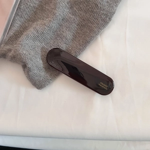 Macro detail of glossy dark brown acetate hair clip with gold France Handmade lettering