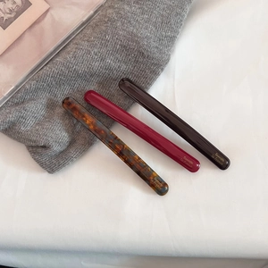 Detailed close-up of three elegant acetate hair clips in tortoise and solid dark colors
