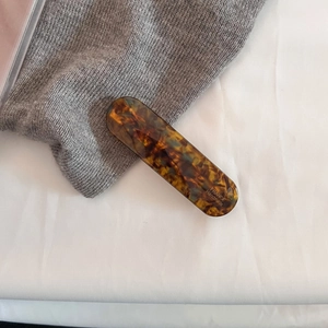 Detail of tortoise shell acetate hair clip with France Handmade lettering on knit fabric