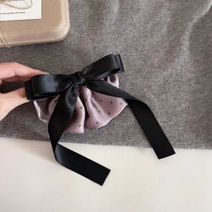 Detail view of double-layered satin bow hair clip with polka dots and soft ribbon tails