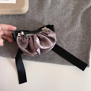 French vintage polka dot bow hair clip with long black ribbons on a grey knit surface
