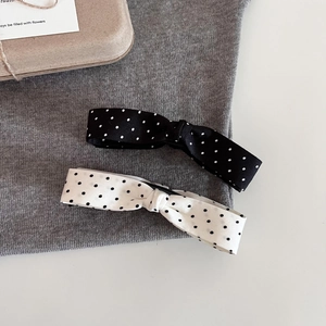 Detail view of retro polka dot bow banana clips in black and white fabric on soft background