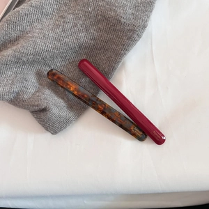 Close-up of elegant acetate hair clips in dark tortoiseshell and deep burgundy glossy finish