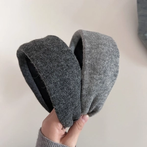 Detail view of two knitted wide-brim headbands in dark and light grey with fabric texture