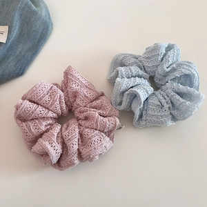 Close-up of pink and light blue lace scrunchies with intricate hollowed textures