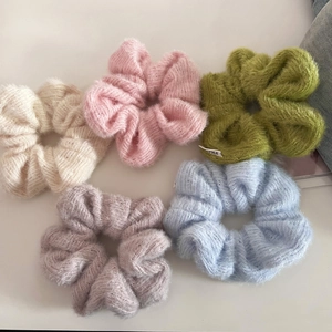 Detailed macro view of five colorful plush knit scrunchies in soft pastel tones
