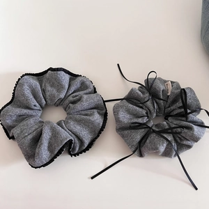 Detail of gray knitted hair scrunchies with black lace trim and handmade ribbon bows