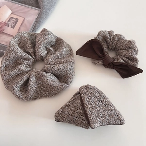 Close-up of knit scrunchies in taupe brown with bow detail and textured fabric