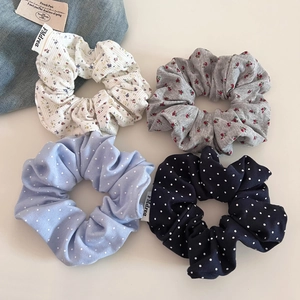 Quatre chouchous en tissu à fleurs et à pois avec étiquettes de marque sur fond beige