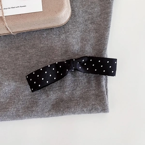 Close-up of black and white polka dot bow hair clip on grey knit fabric background