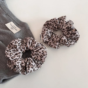 Close-up of two knit leopard print scrunchies with elegant fabric texture and elastic design
