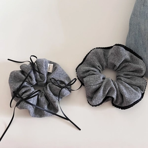 Detail of gray knit hair scrunchies with black bow ribbons and handmade fabric label