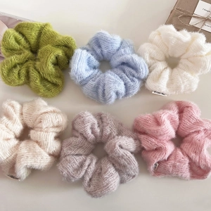 Detailed close-up of six colorful ribbed knit scrunchies in soft pastel tones