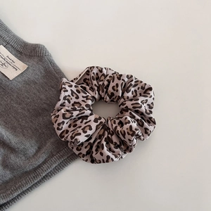 Detail of plush leopard print scrunchie showing fabric texture and elastic pleats