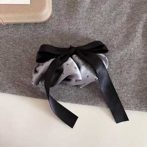 Detail of silk hair scrunchie with grey polka dots and oversized black satin bow