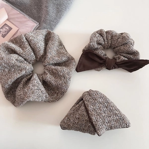 Detailed view of winter brown knit hair ties set with bow on white soft background