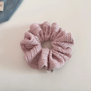Detail of light pink lace scrunchie with hollow floral pattern and soft mesh texture