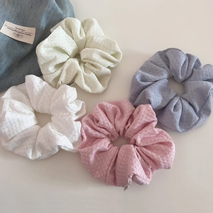 Close-up of four colorful knit scrunchies in cream, pink and purple with texture