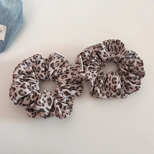 Set of two vintage leopard print knit scrunchies with white labels on grey background