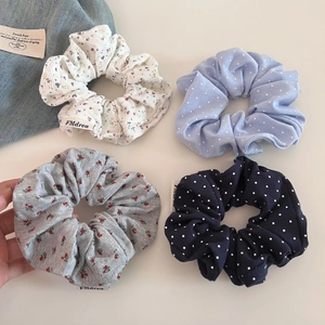 Détail de quatre chouchous en tissu avec motifs floraux, pois et texture côtelée