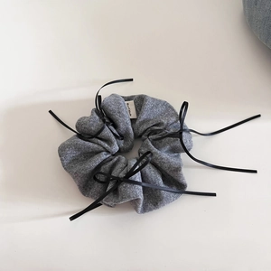 Detail of grey knitted hair scrunchie with black ribbons and Hand Made woven label