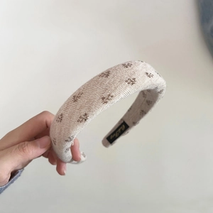 Detail of knitted sponge headband with vintage floral pattern and brand inner label