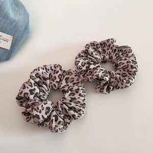 Close-up of leopard print scrunchies with soft fabric texture and a white woven brand label