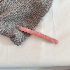 Detailed view of pink marble acetate hair clip with silver metal base on fabric