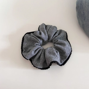 Detailed close-up of grey knitted bow hair scrunchie with black pleated lace edges